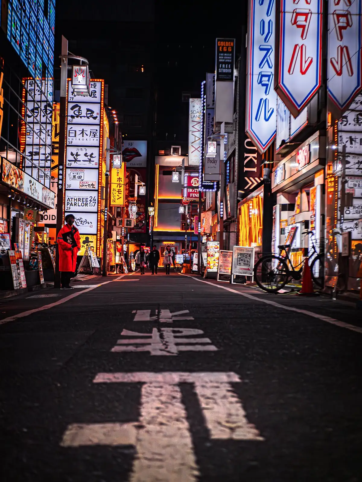 Calle de Tokio de noche, llena de carteles luminosos